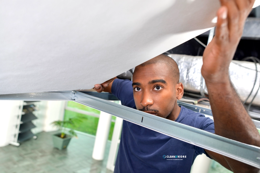 Young African American man inspecting ceiling tiles. Facility Maintenance and ceiling tile replacement Nashville, TN
